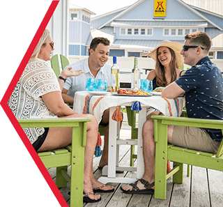 Four people sitting at a table outside a cabin laughing.