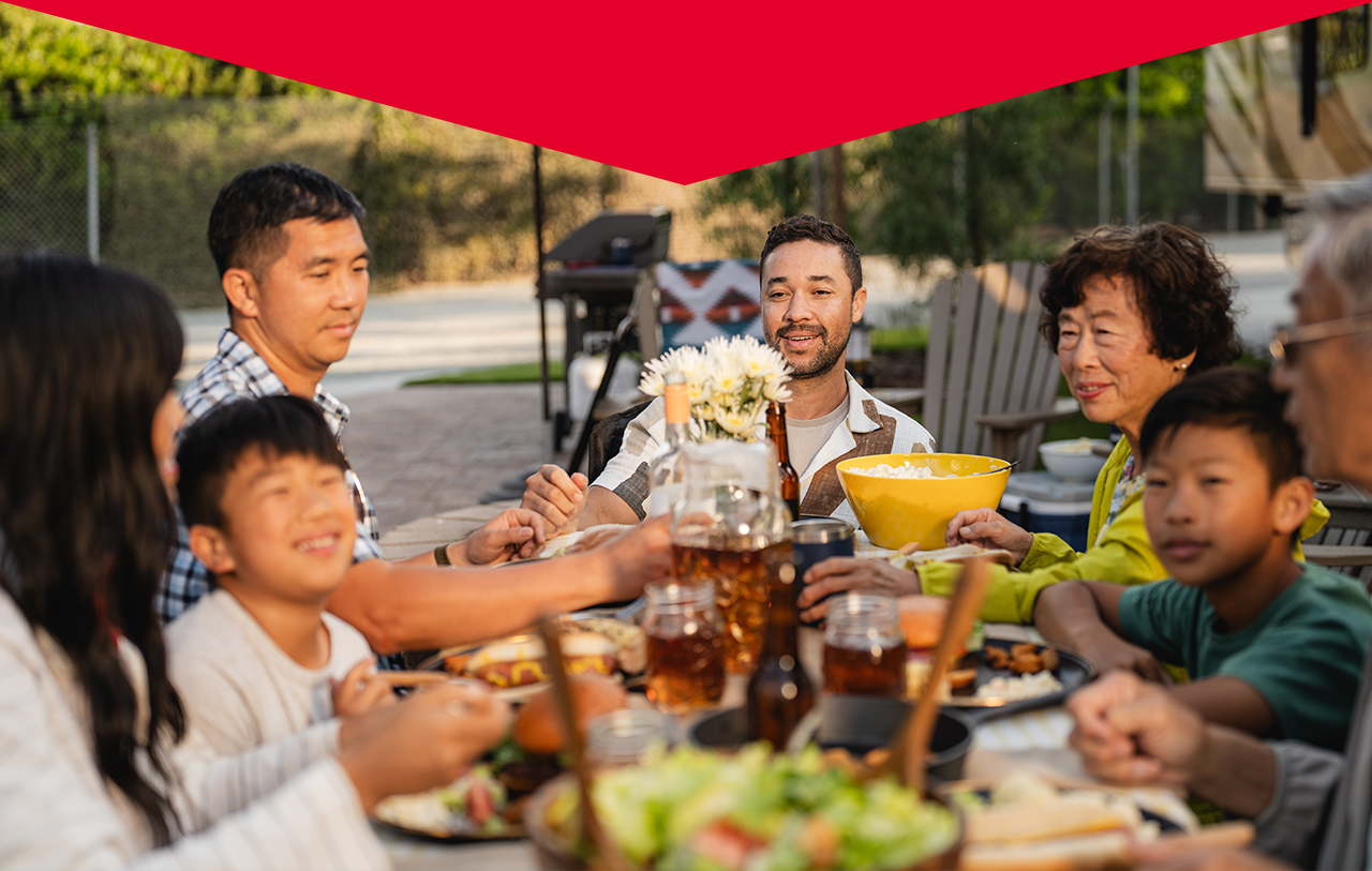 A family sitting at a table outside enjoying a meal.