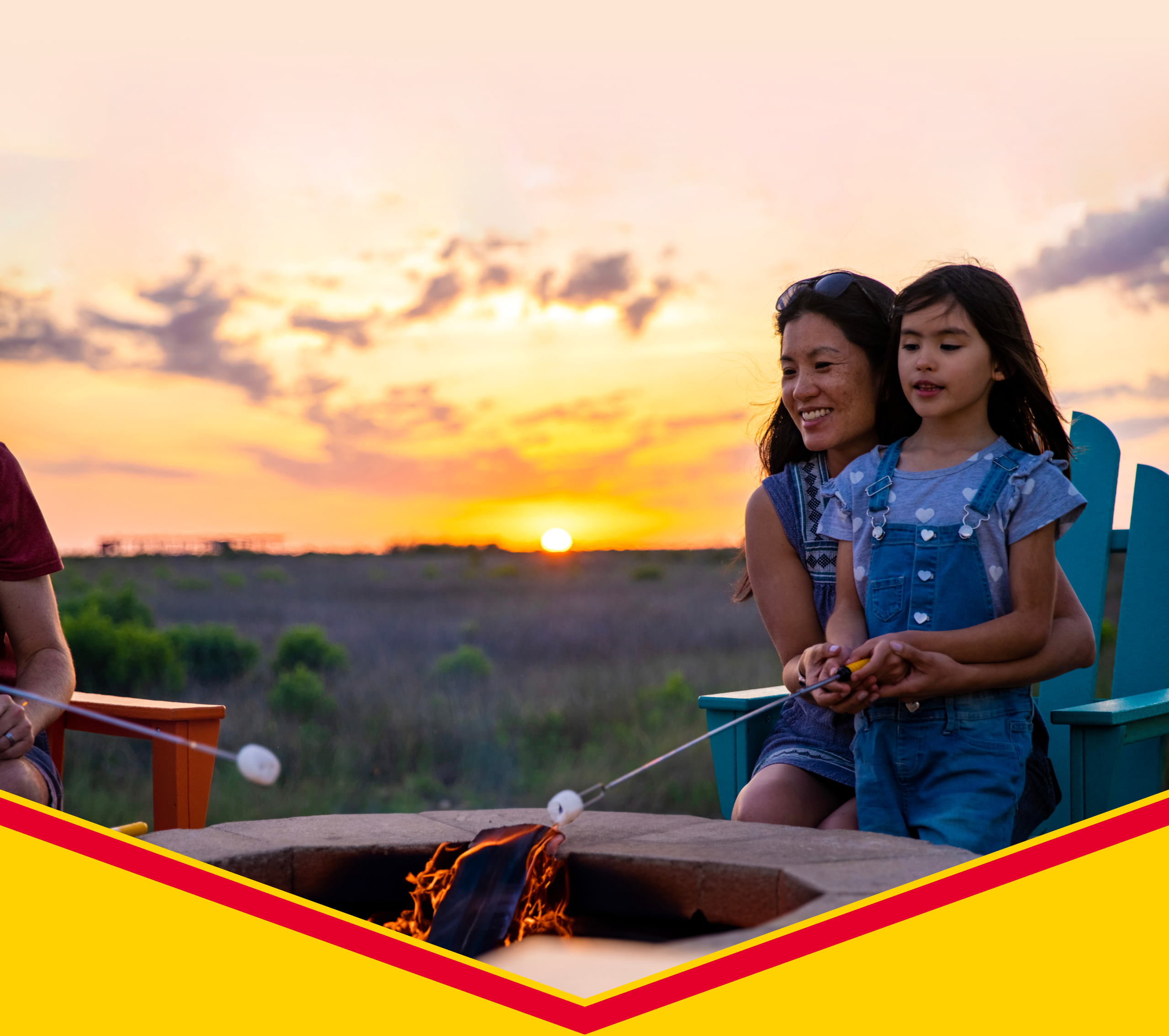 A mom and daughter roasting marshmallows in a firepit.