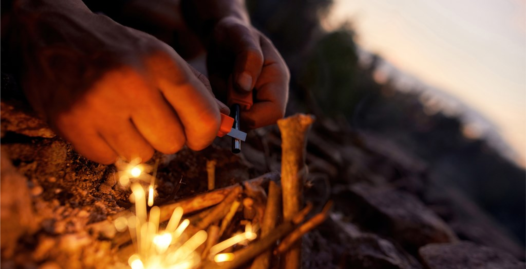  A pair of hands sparking a flint to light a campfire.