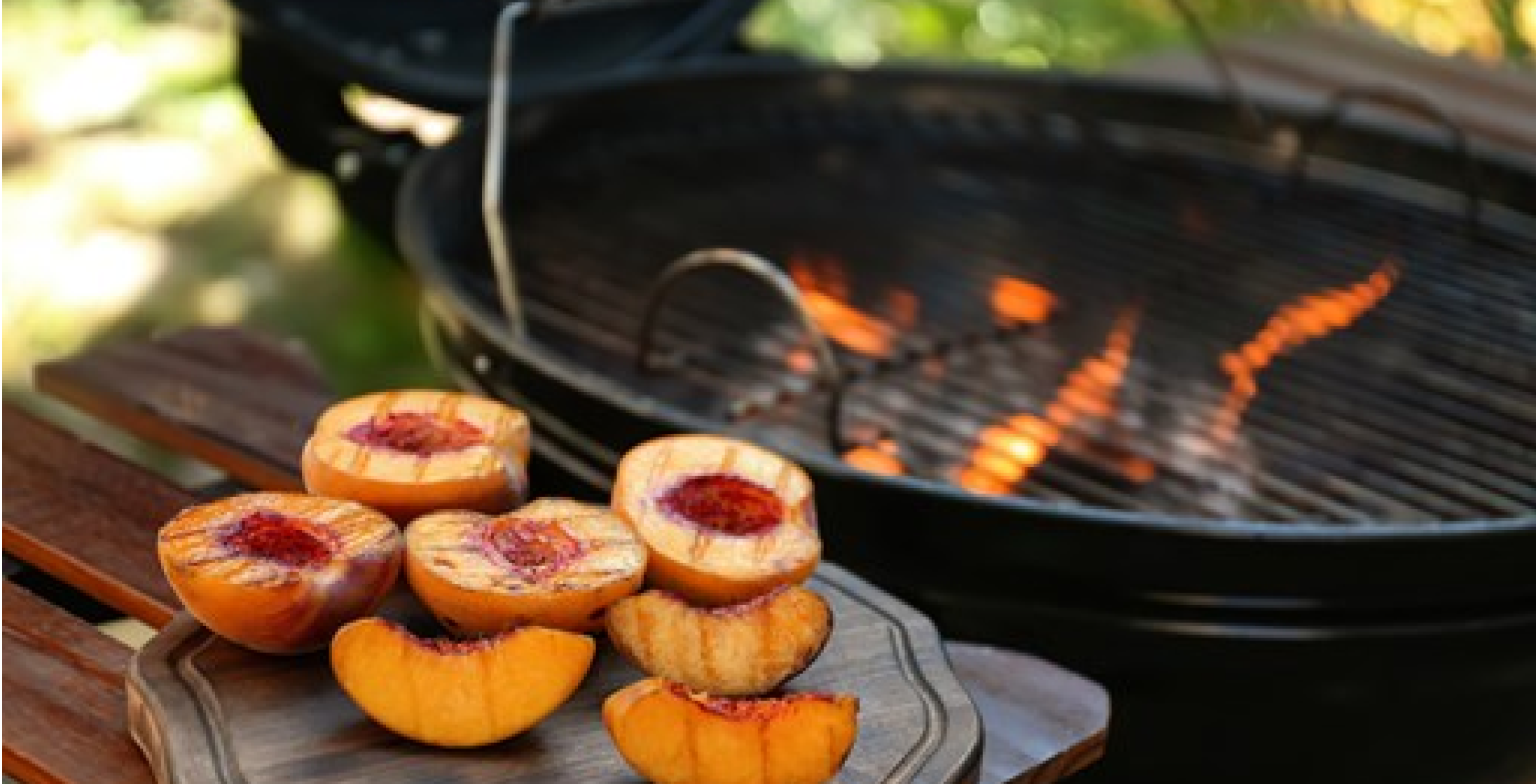 Grilled peach slices near a grill.