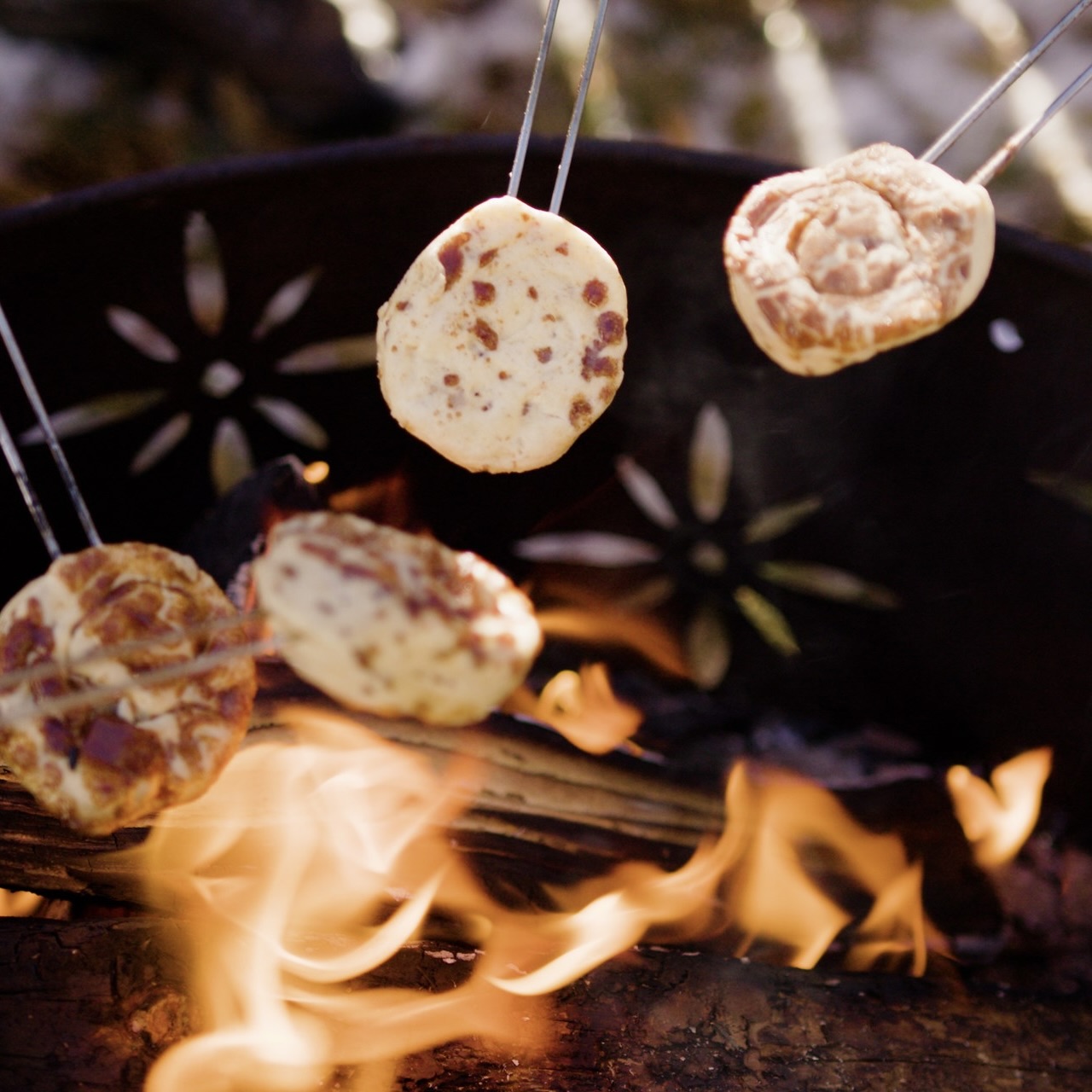 Unbaked cinnamon rolls being roasted over a campfire