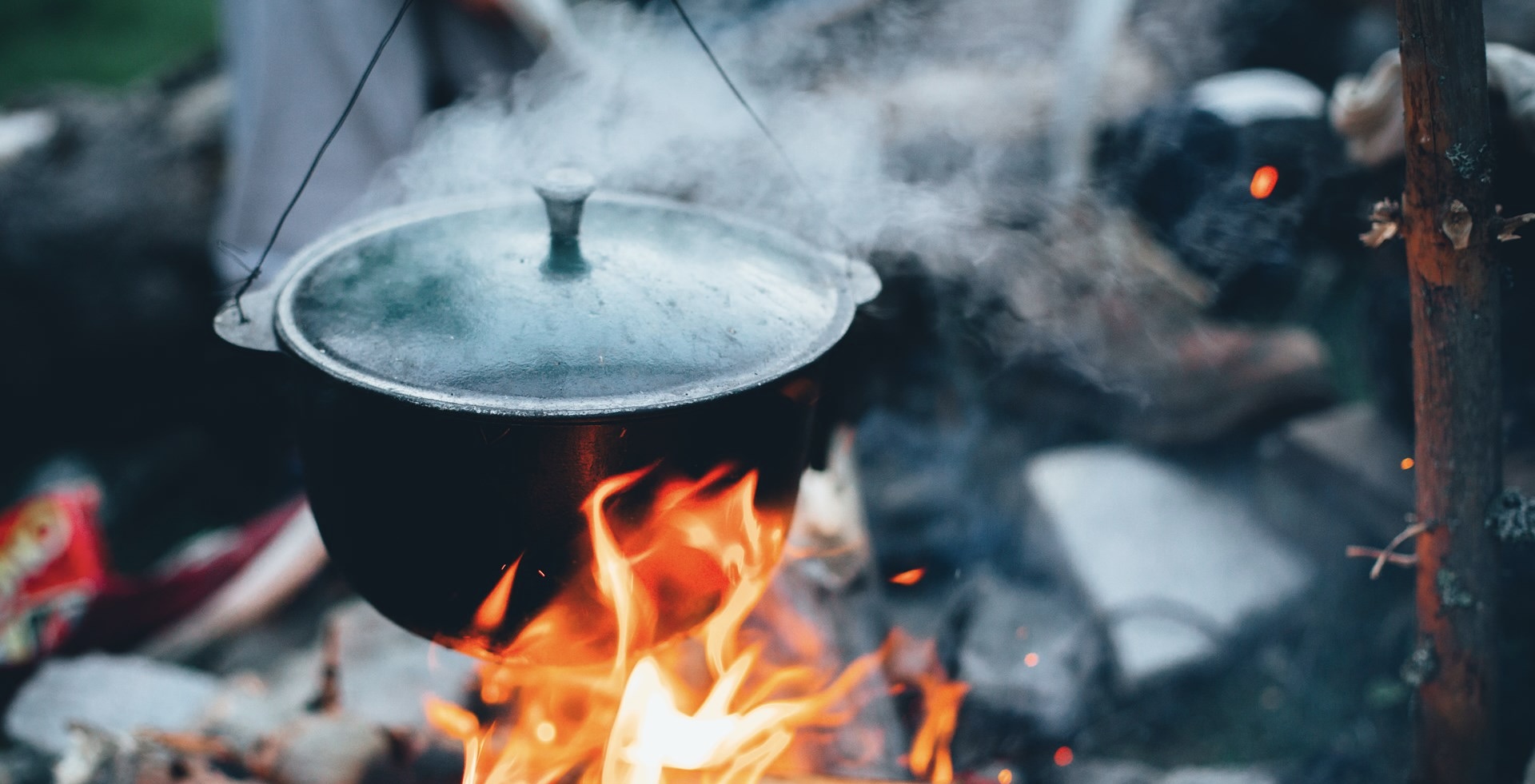 A cast iron dutch oven hanging of a campfire