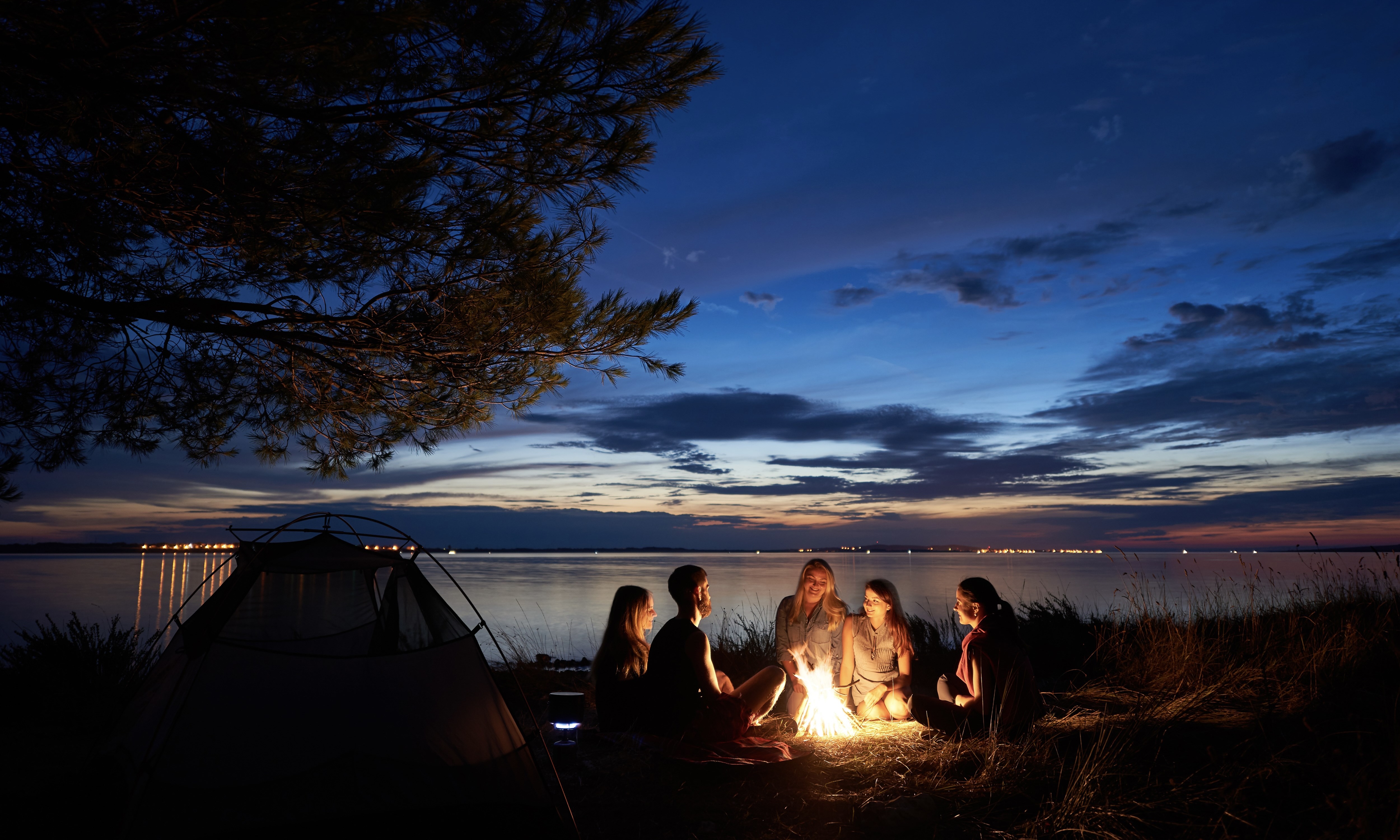 A group of friends gathered around a campfire at nighttime