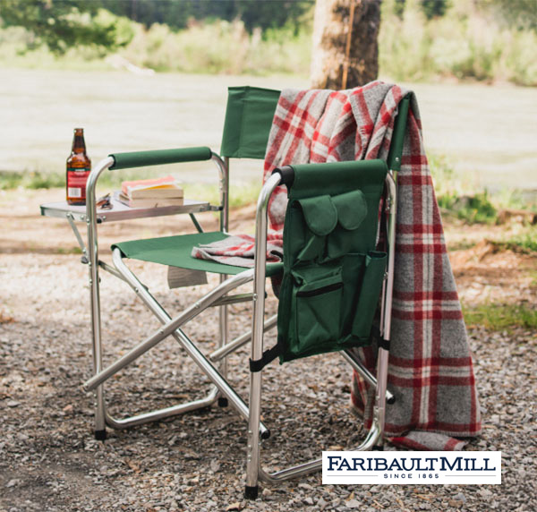 A folding outdoor chair with a Faribault blanket draped over the back at an outdoor campsite in the daytime.