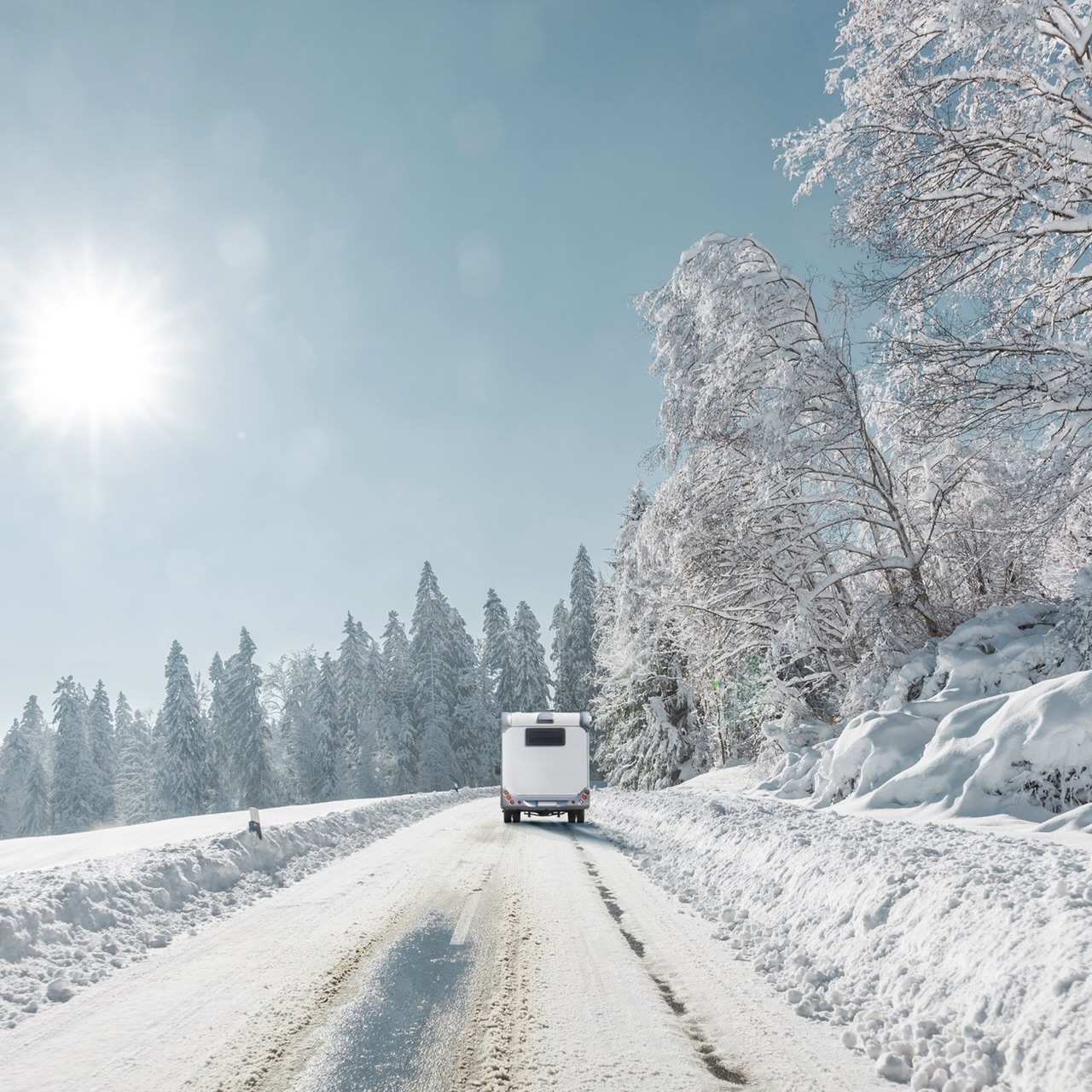 An RV driving down a snowy road in the daytime