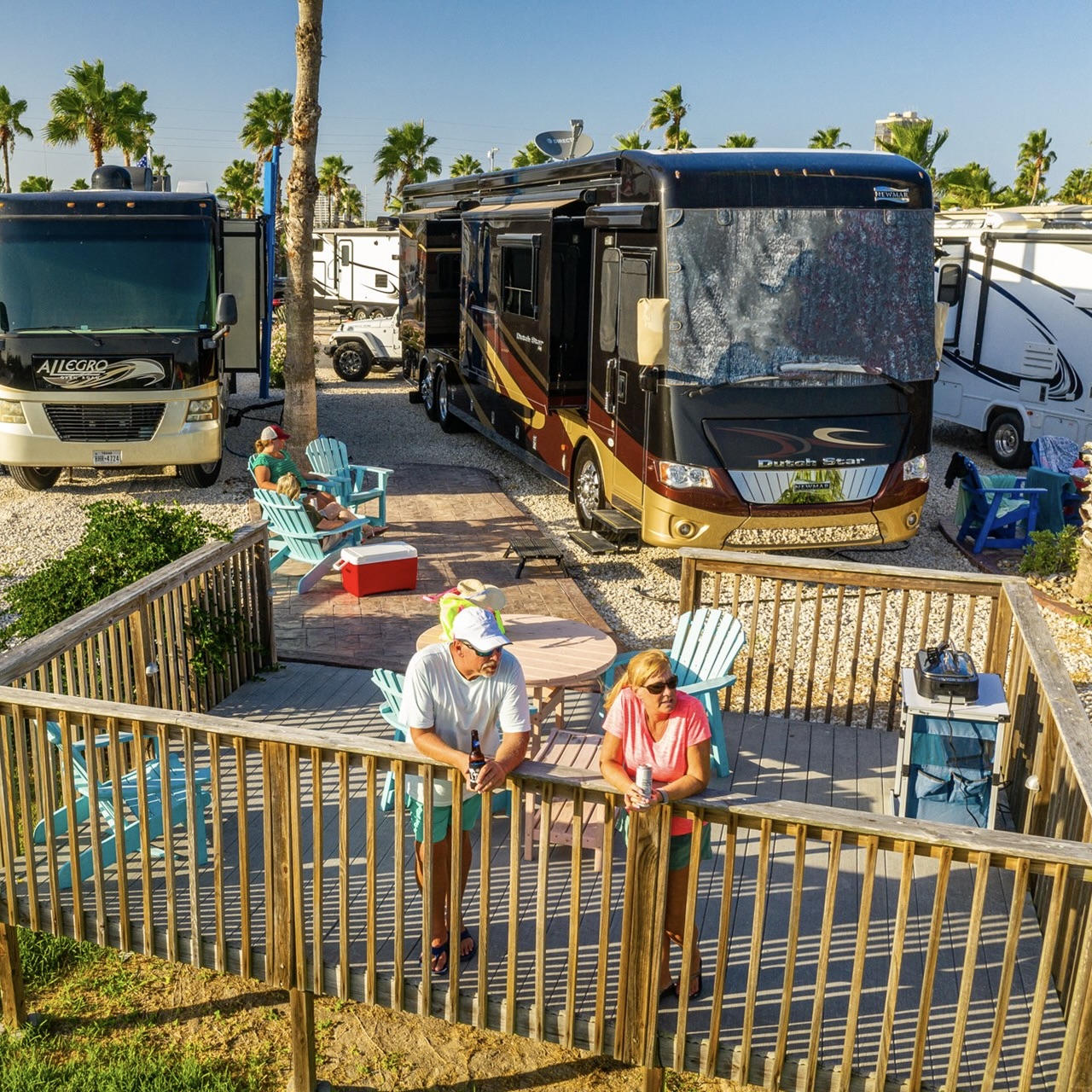 A couple standing on a wooden deck near an RV at a KOA campground in the daytime